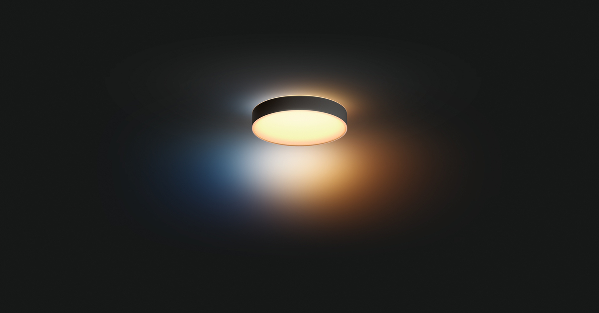 Lámpara de techo redonda emite luz cálida contra una pared oscura.