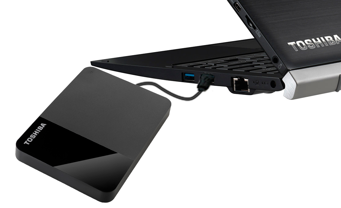 A Toshiba external hard drive is connected to a Toshiba laptop via a cable.