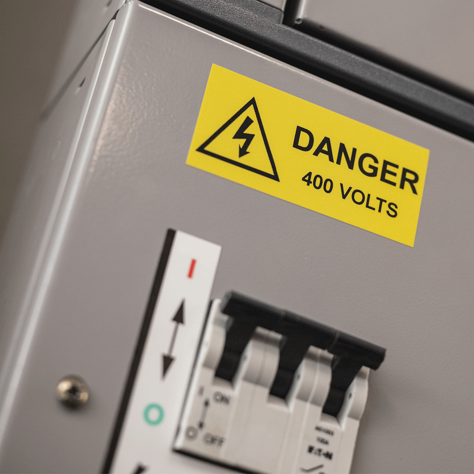 A grey electrical panel with a yellow warning sticker reading "Danger 400 Volts" and a black circuit breaker.