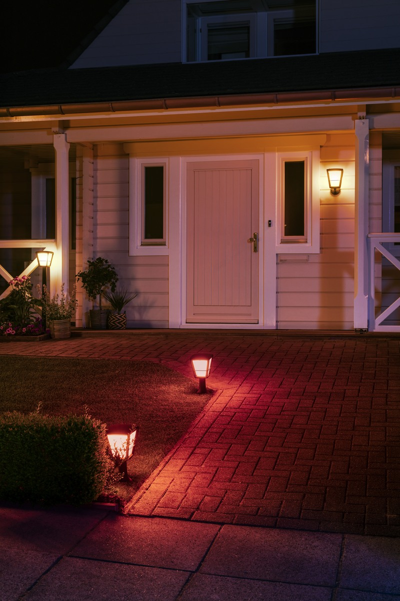 Illuminated house entrance at night with red pathway lights and warm wall light.