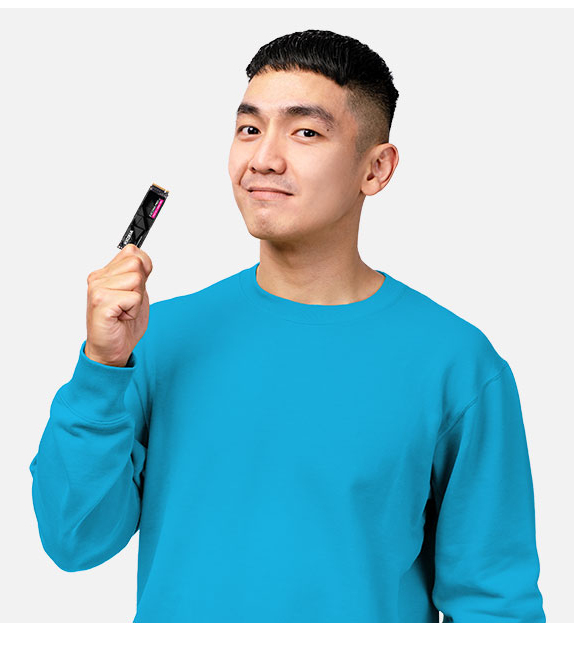 A young man in a blue sweater holds up a small black component.
