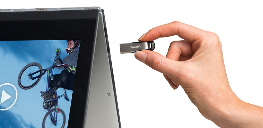 Ręka trzyma pamięć USB w pobliżu portu laptopa.