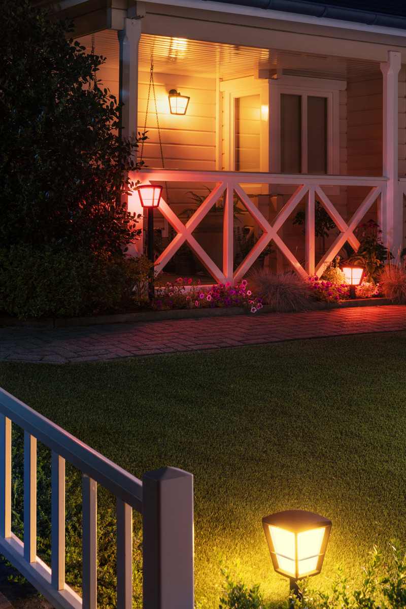 Beleuchtete Veranda und Garten bei Nacht mit warmem Licht und bunten Blumen.