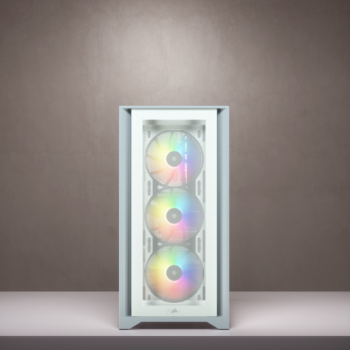 Ein weißer PC-Gehäuse mit drei leuchtenden RGB-Lüftern vorne steht auf einem Tisch vor einer grauen Wand.