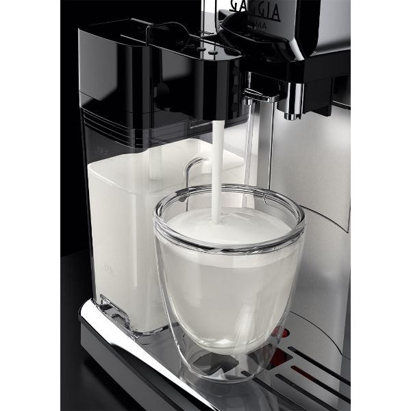 A coffee machine pours milk into a double-walled glass.