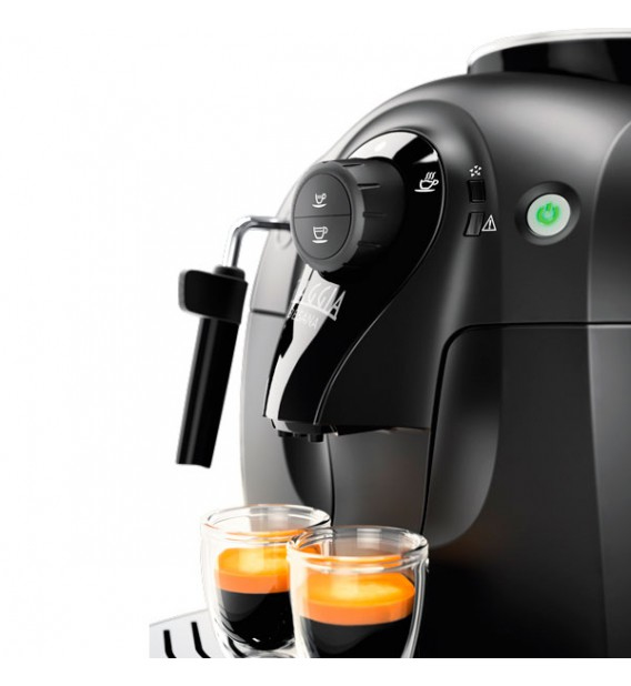 Una cafetera negra llena dos tazas pequeñas de vidrio con espresso recién hecho.