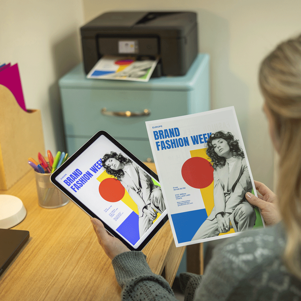 Eine Frau hält ein Tablet und ein Plakat für die Brand Fashion Week in den Händen.