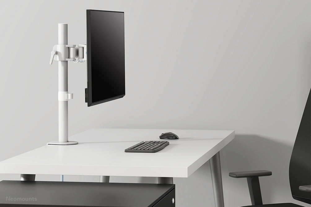 A white desk with a monitor arm, a black monitor in portrait mode, keyboard, mouse, and a chair.