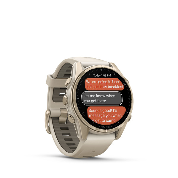 Smartwatch Garmin beige che mostra messaggi di testo sullo schermo rotondo su sfondo bianco.