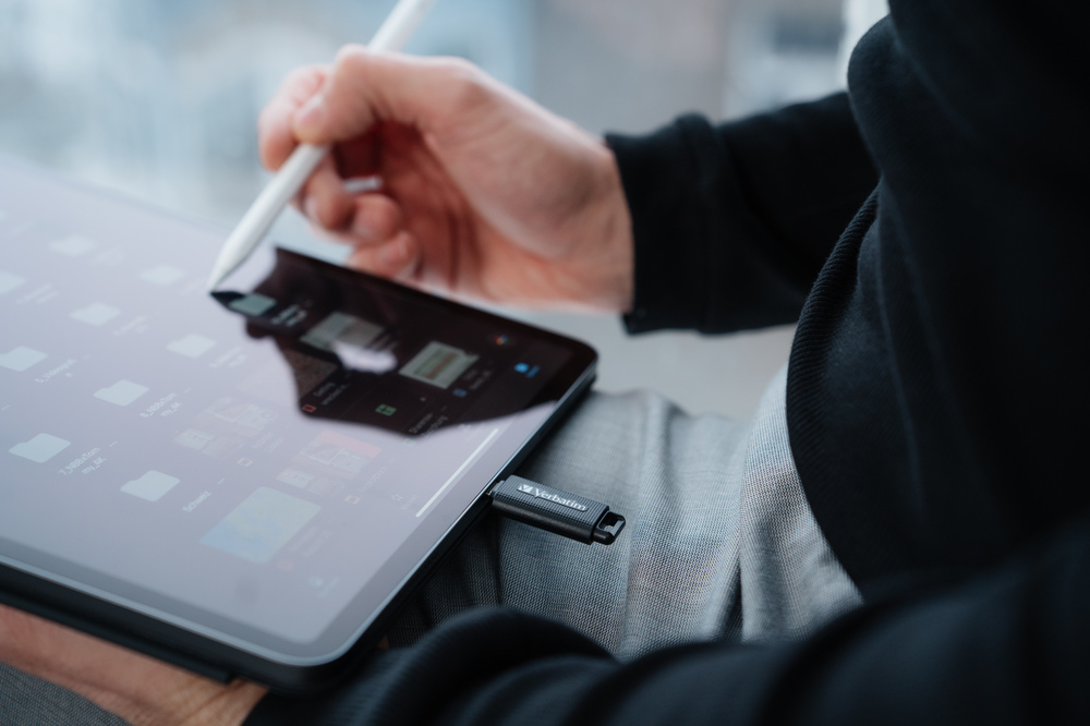 Una persona usa un lápiz óptico en una tableta con una unidad USB conectada.