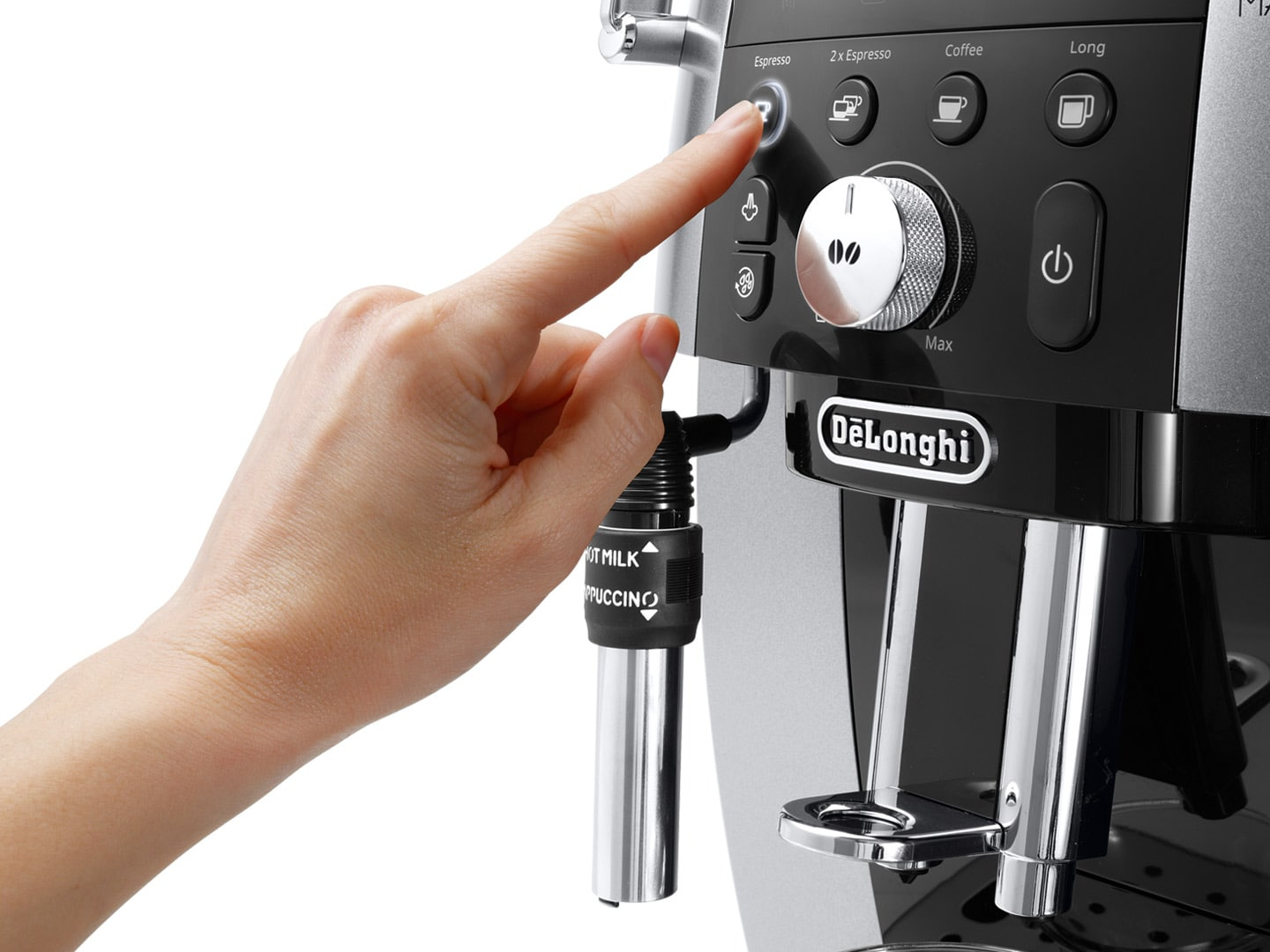 Una mano preme il pulsante dell'espresso su una moderna macchina DeLonghi.