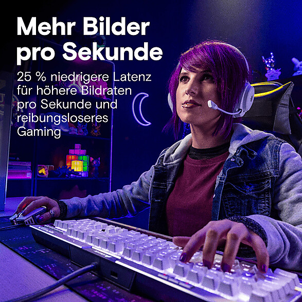 Eine Spielerin mit violetten Haaren sitzt an einem Schreibtisch, benutzt Tastatur und Maus und trägt ein Headset.