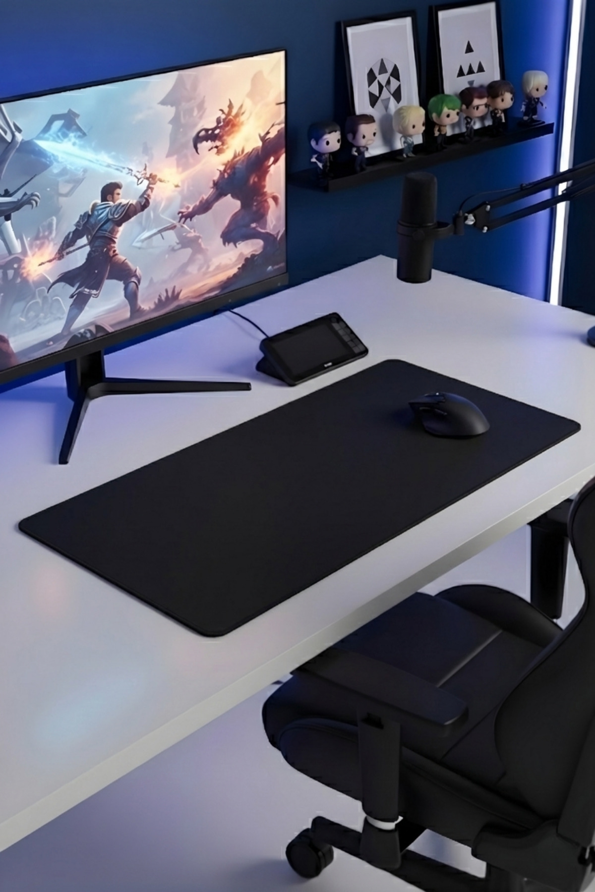 Monitör, büyük siyah mousepad, fare ve sandalye içeren modern oyun masası.