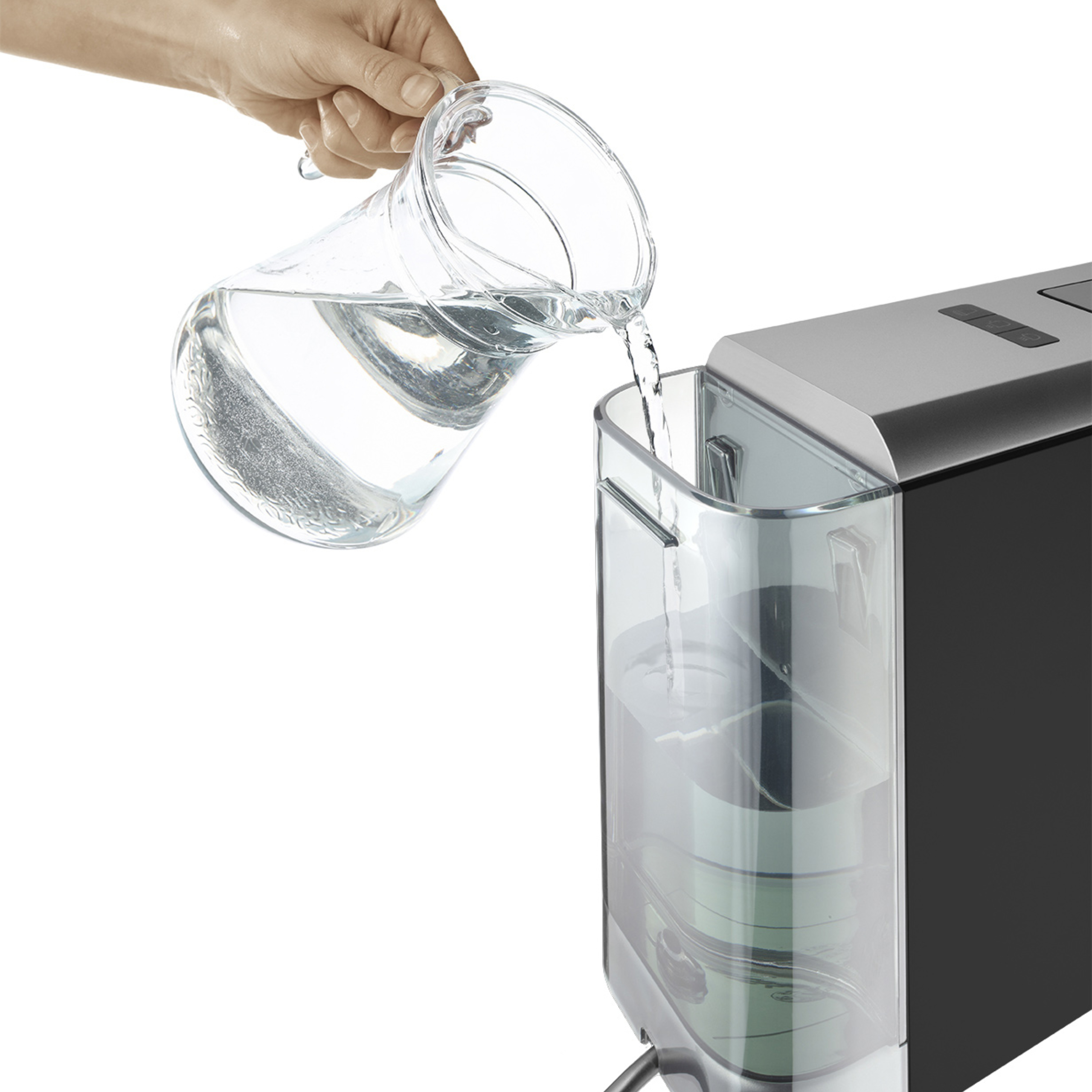Eine Hand gießt Wasser aus einer Glasurkaraffe in den Wassertank einer Kaffeemaschine.