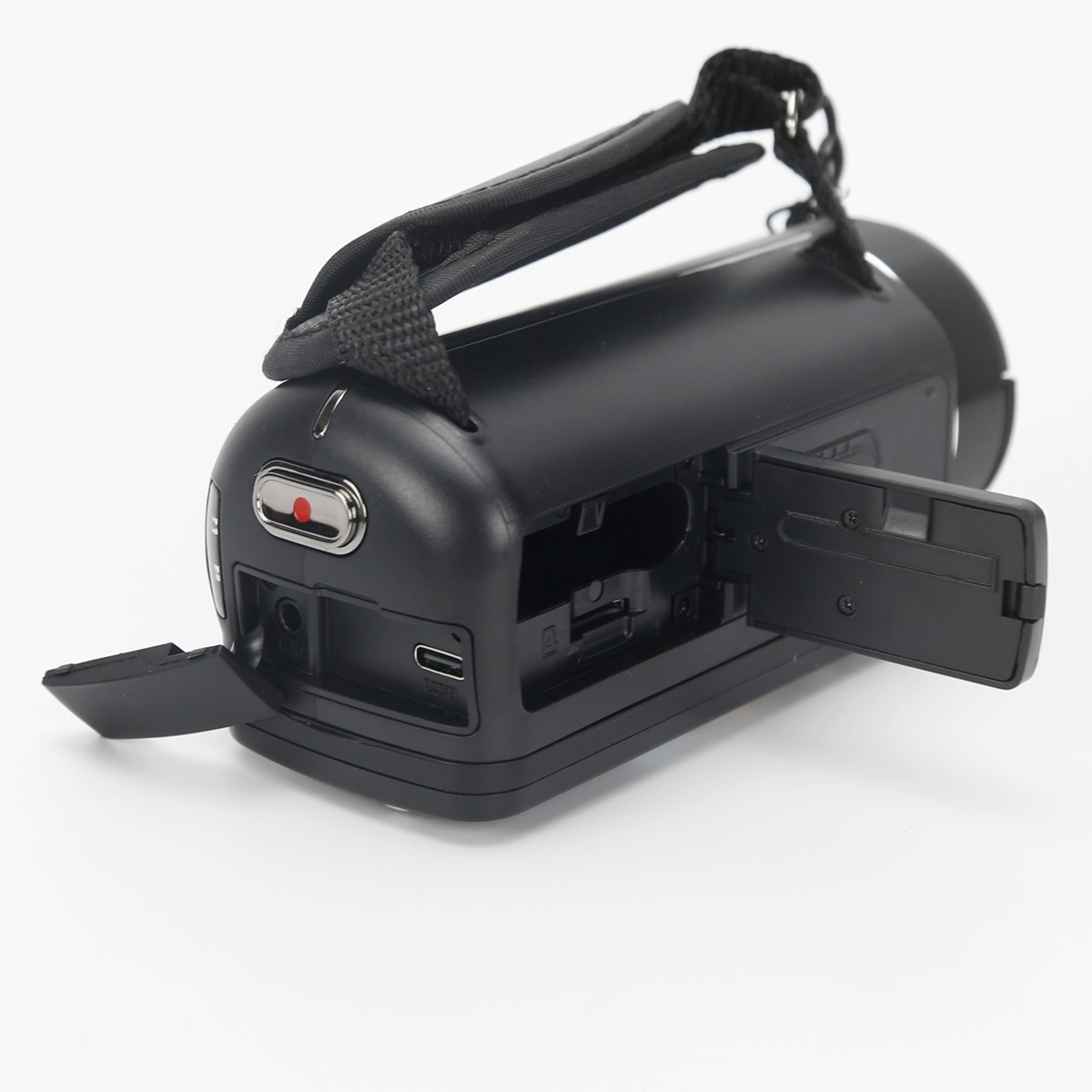 Black video camera with an open battery compartment and a hand strap on a light background.