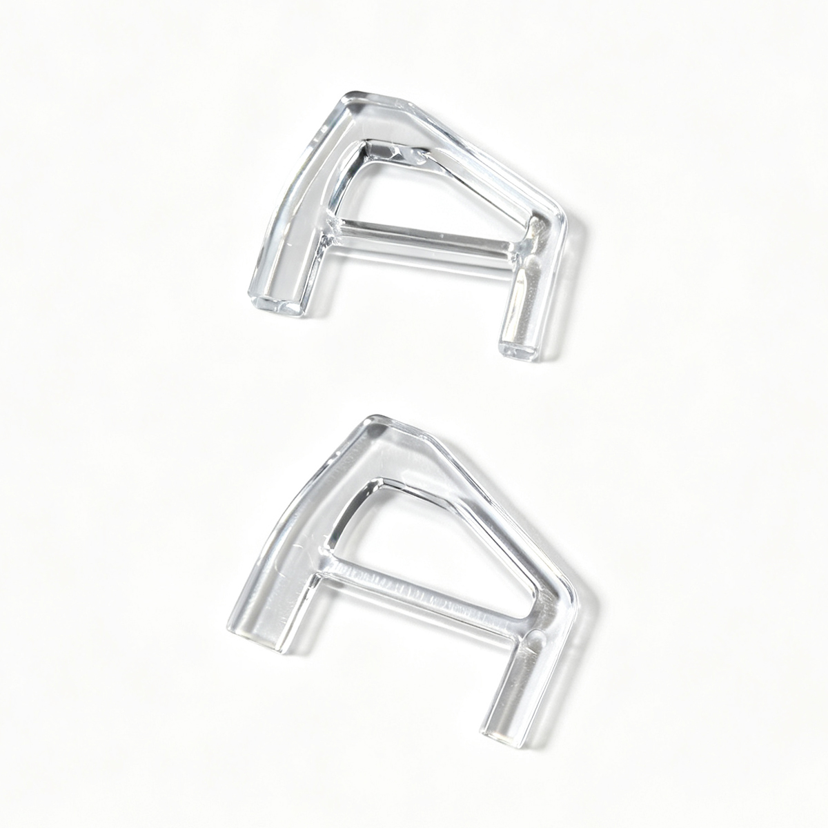 Two transparent, letter-shaped plastic pieces lie on a white surface.