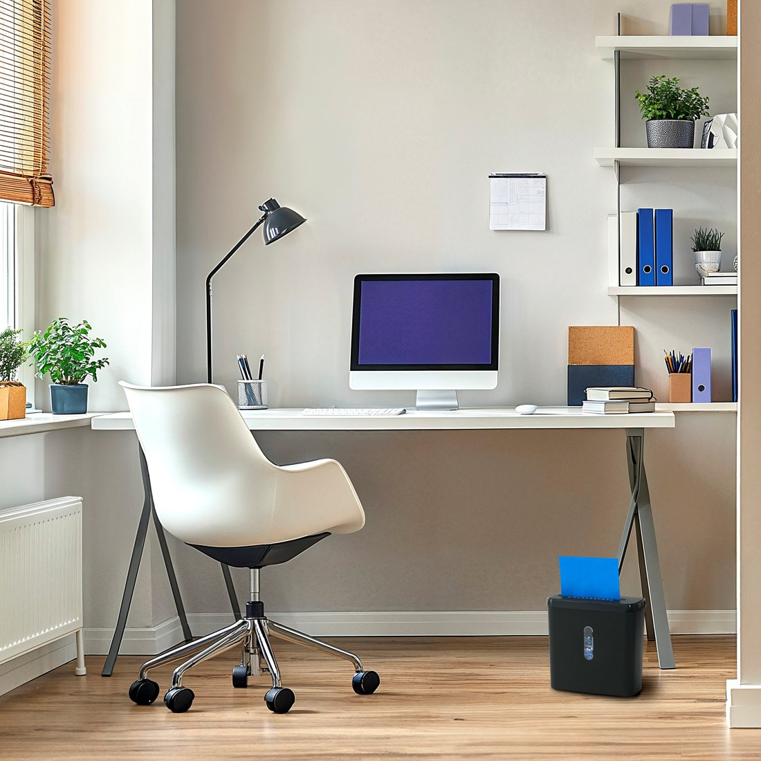Moderne Schreibtisch-Setup mit Computer, weißem Stuhl, Lampe und Regalen an einer grauen Wand.