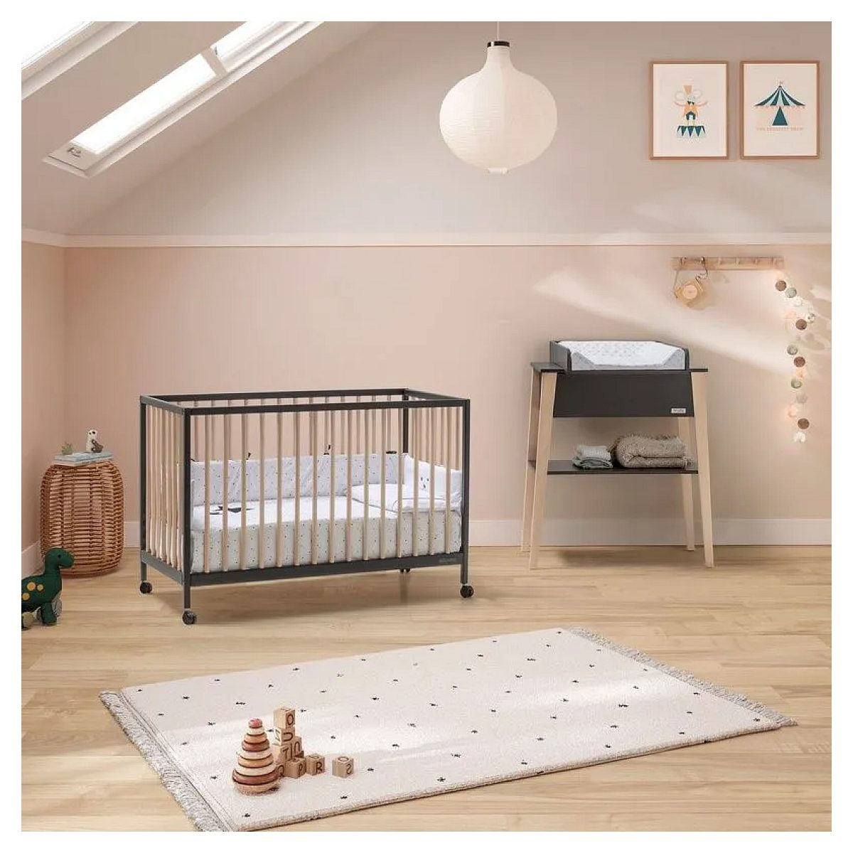 Gemütliches Kinderzimmer mit dunklem Gitterbett, Wickeltisch, Holzwürfeln auf einem Teppich und Dachfenster.