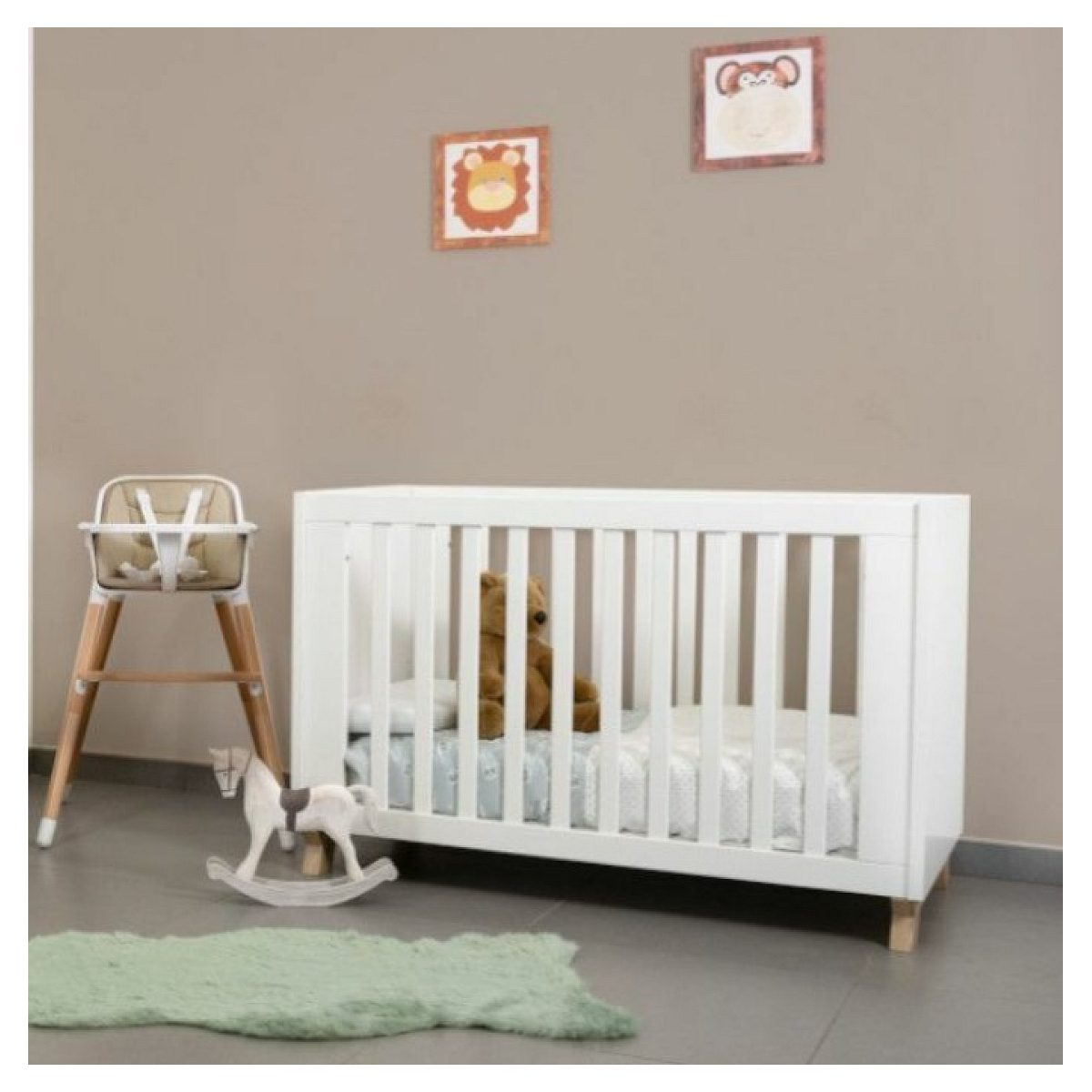 Ein weißes Babybett mit Teddybär, daneben ein Hochstuhl, Schaukelpferd und Tierbilder an der Wand.