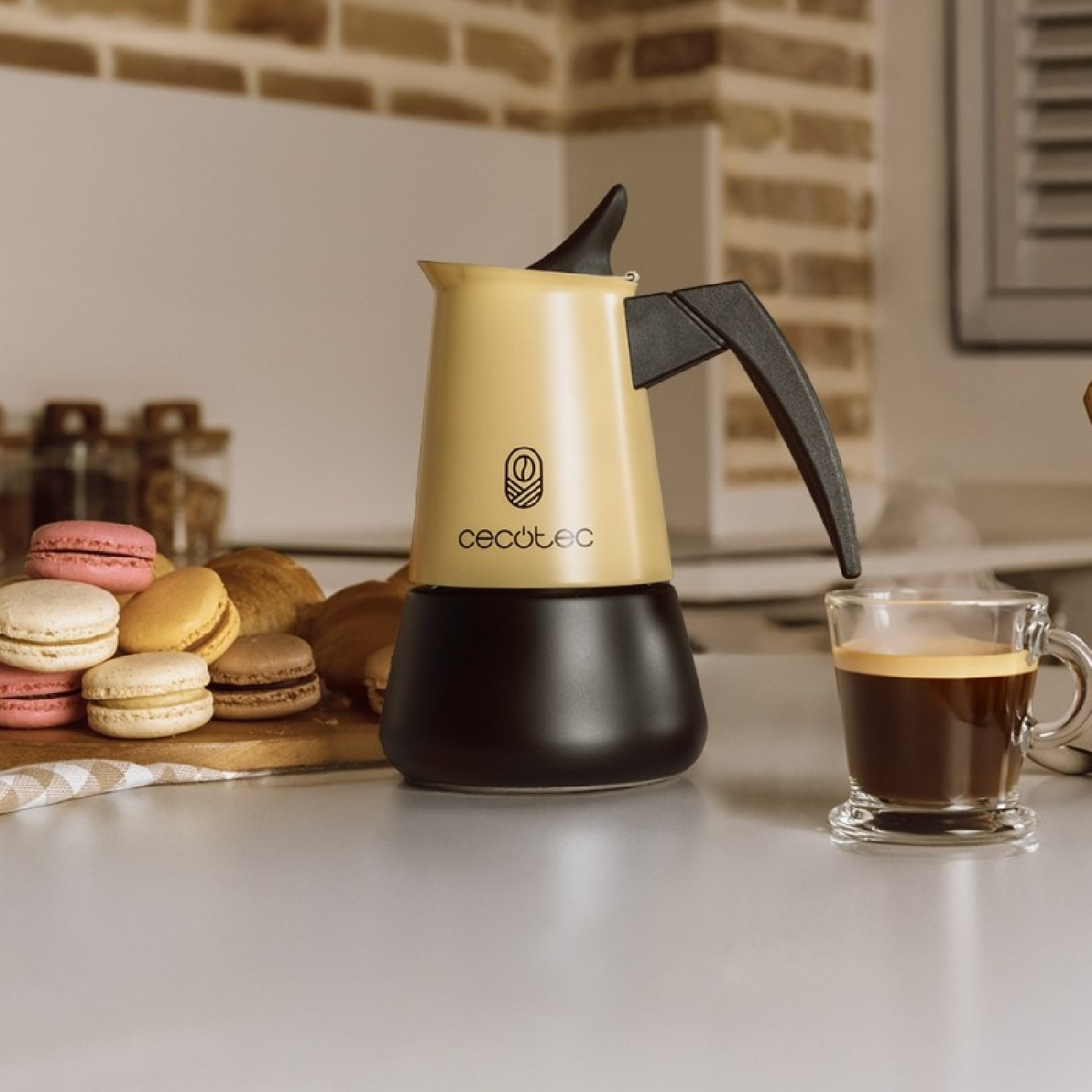 Cafetera moka amarilla y negra en una encimera con macarons y una taza de café.