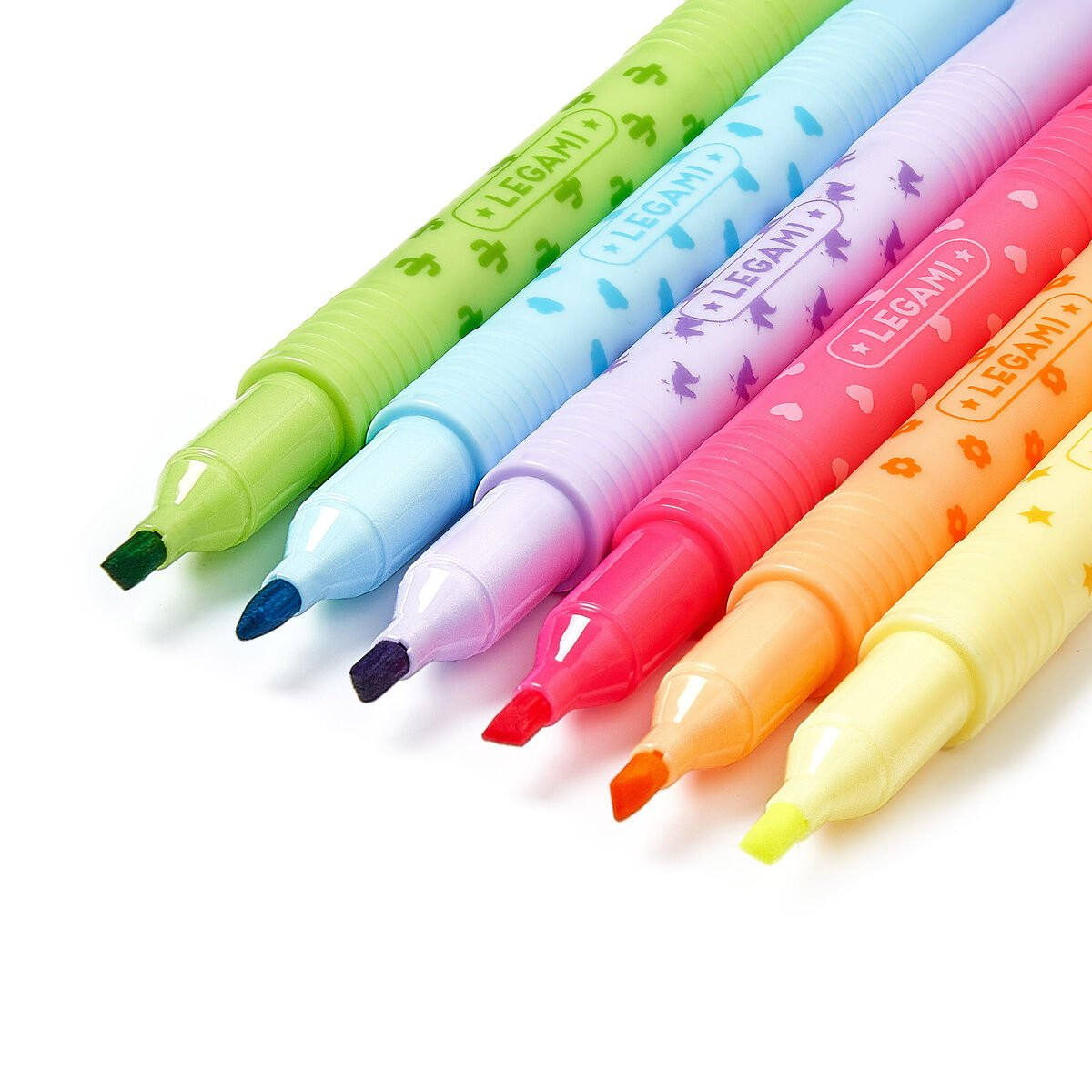 Sechs bunte Legami-Textmarker in Grün, Blau, Lila, Pink, Orange und Gelb liegen diagonal auf weißem Hintergrund.