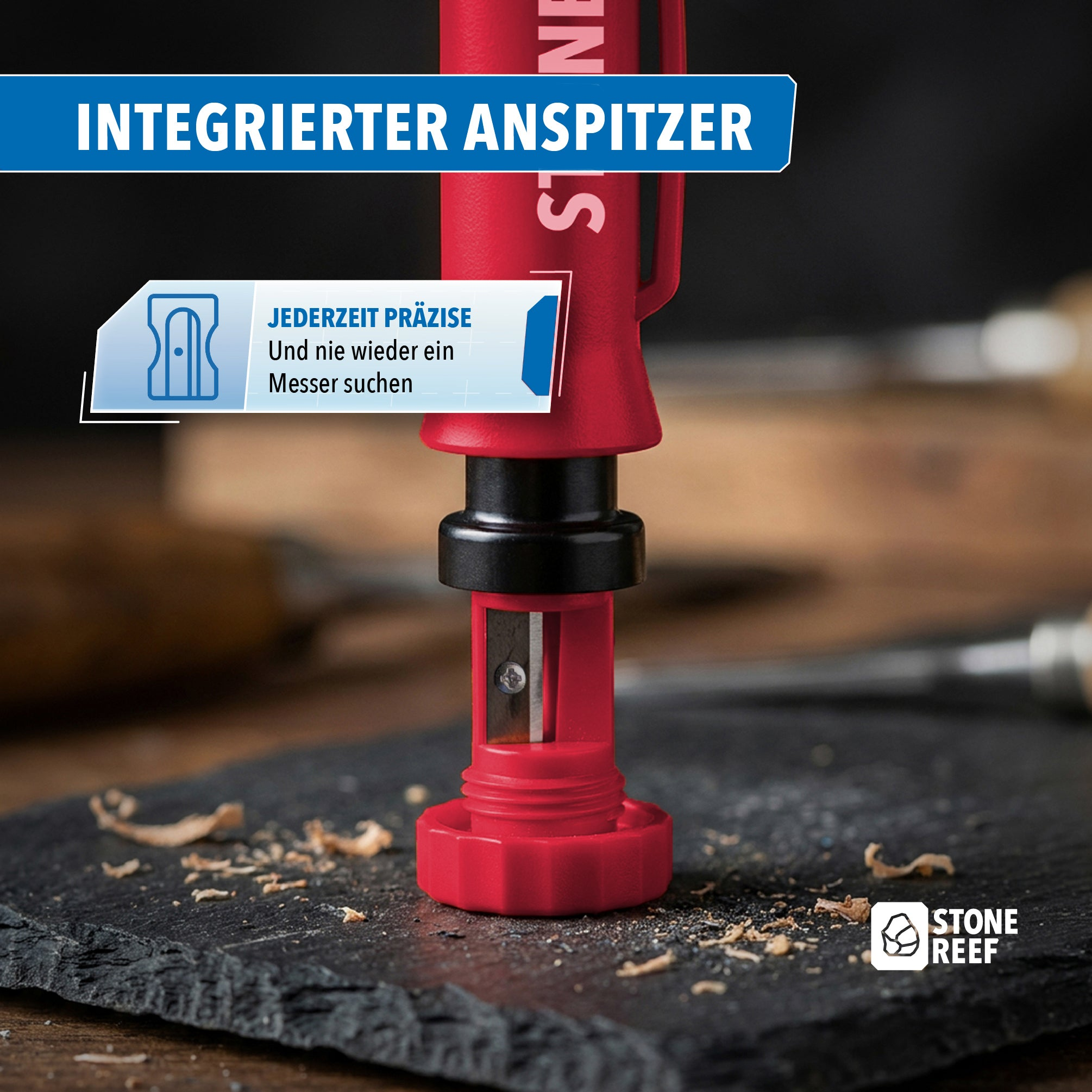 Ein roter Stift mit integriertem Anspitzer steht auf einer Schieferplatte mit Holzspänen.