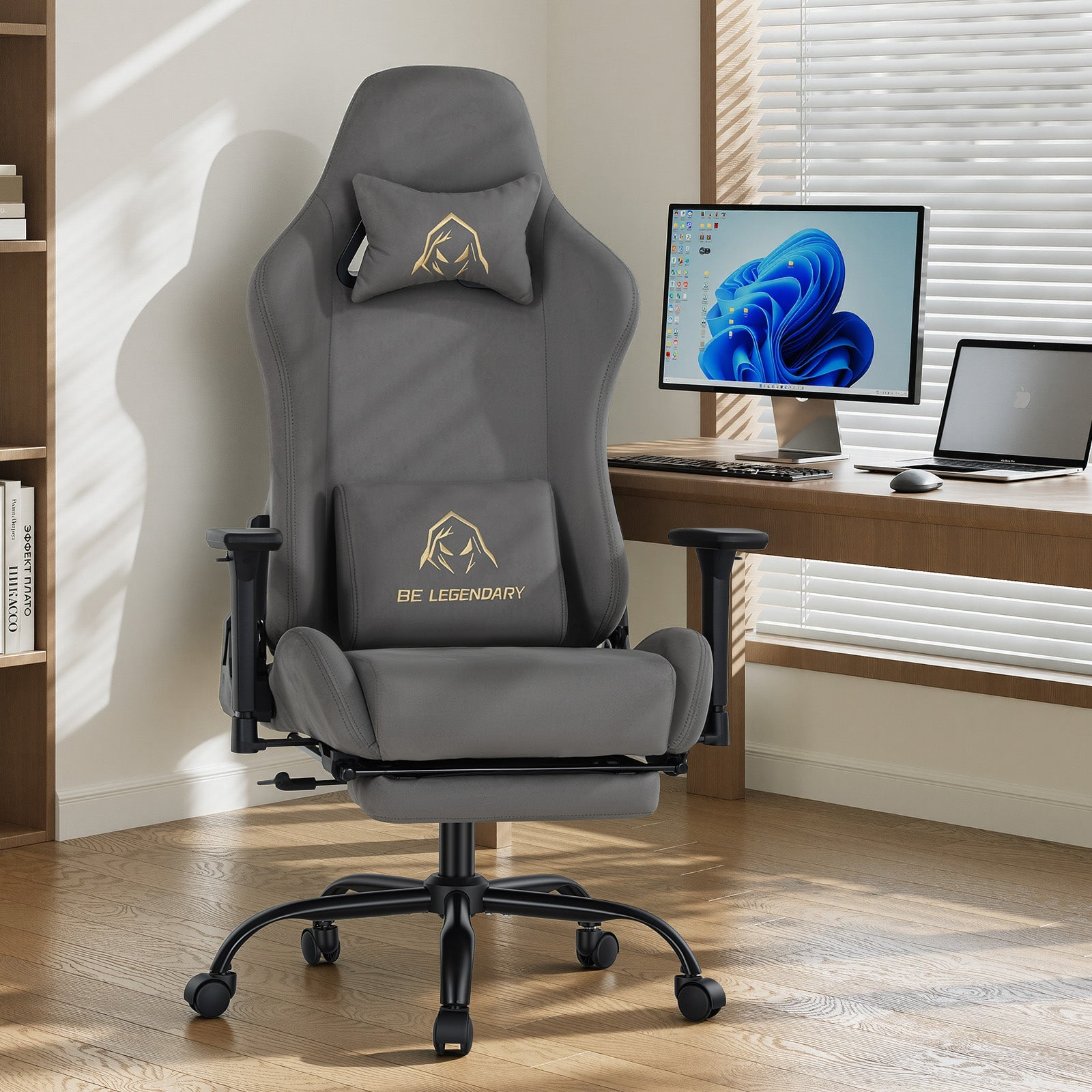 Grauer Gaming-Stuhl mit Fußstütze vor einem Schreibtisch mit Monitor und Laptop.