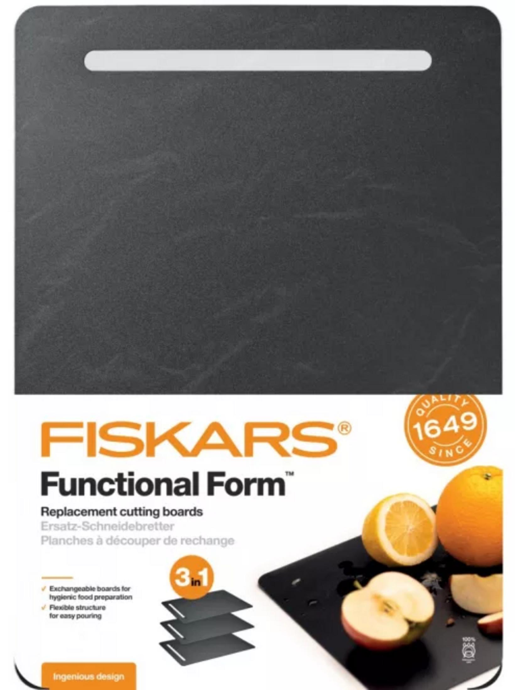 Opakowanie Fiskars Functional Form przedstawiające czarną deskę do krojenia z pokrojonymi owocami.