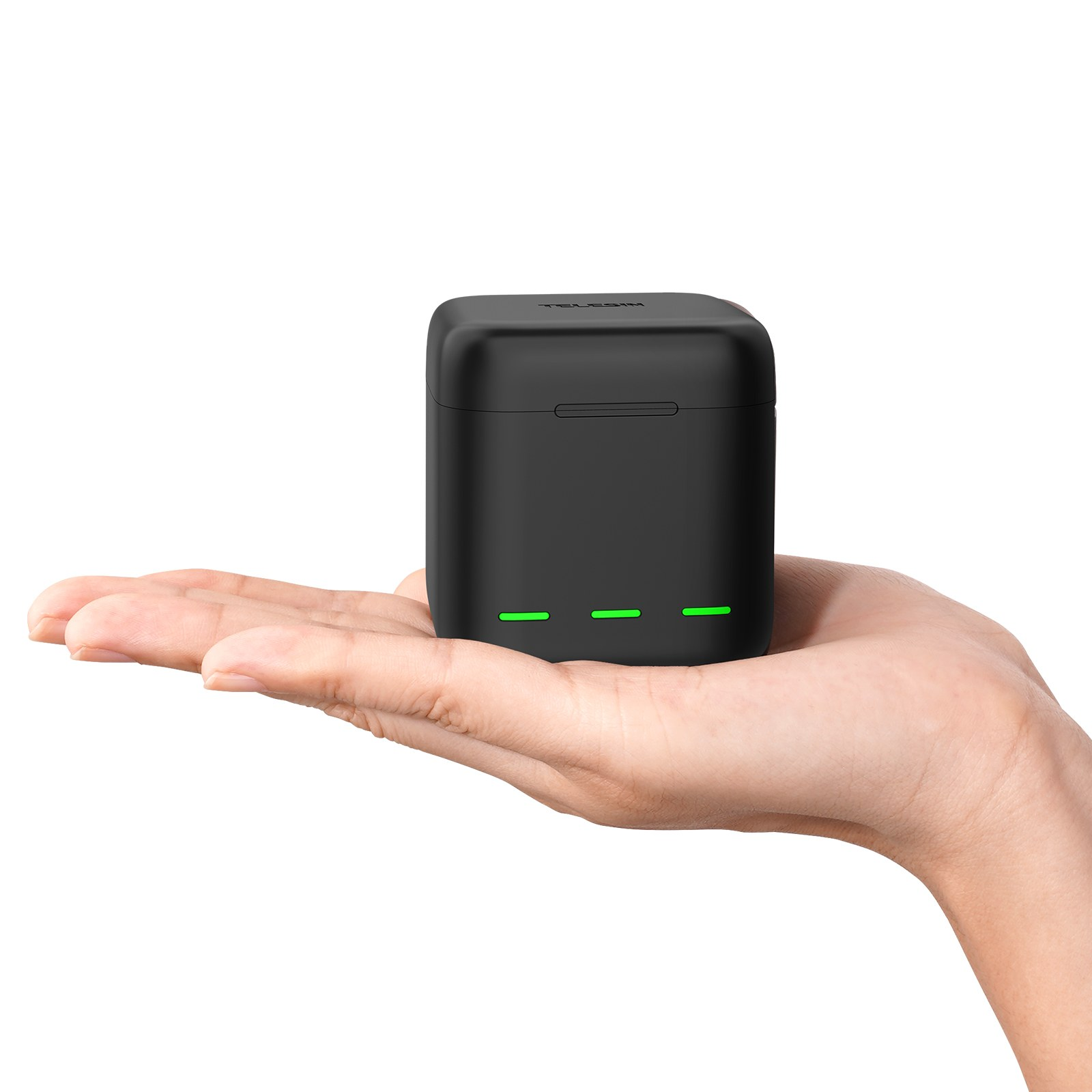 A hand holds a small, black box with three glowing green indicator lights.