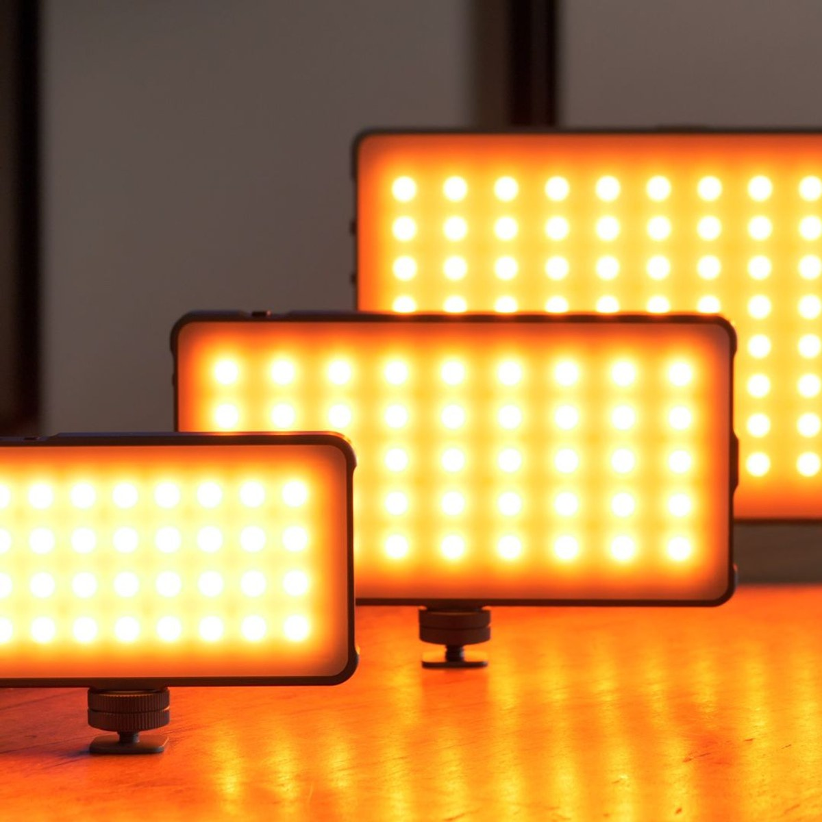 Three LED panels emit warm orange light in a dark room.