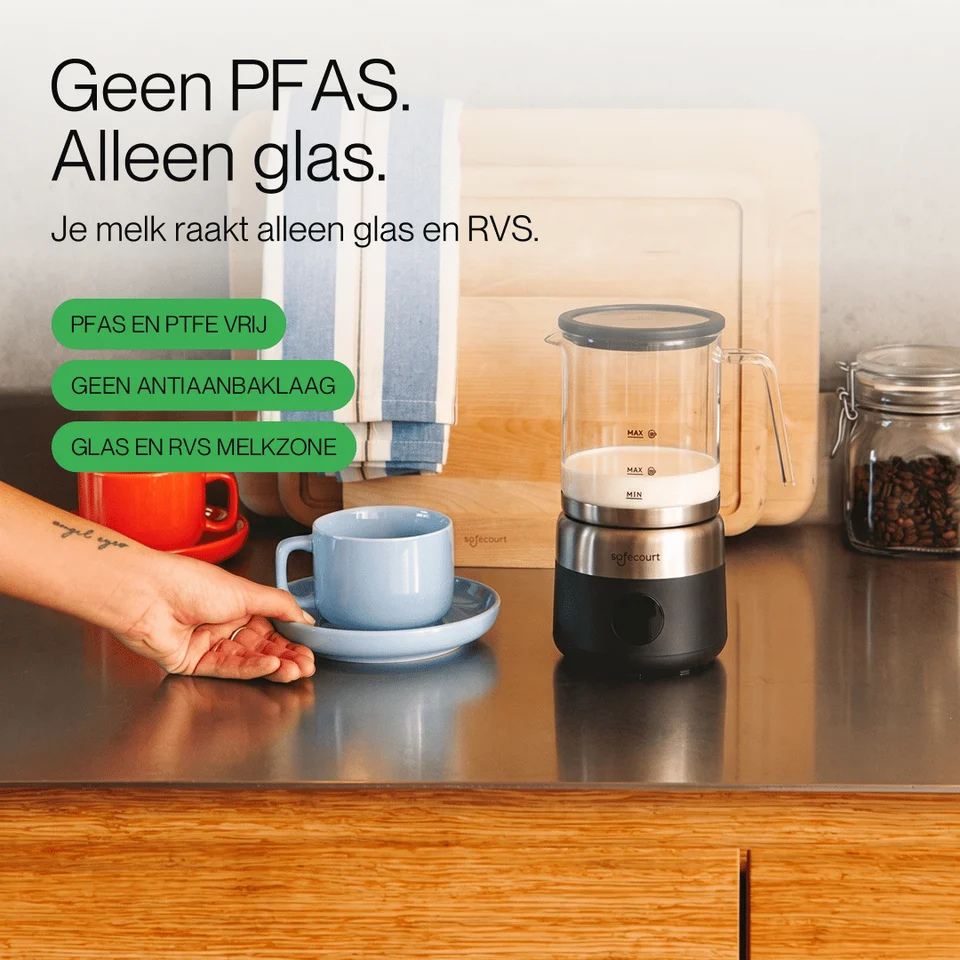 Een glazen melkopschuimer met RVS basis staat op een aanrecht naast een blauw kopje.