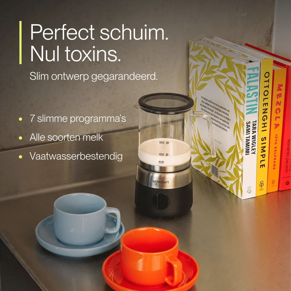 Een melkopschuimer, kopjes op schoteltjes en kookboeken op een aanrecht.