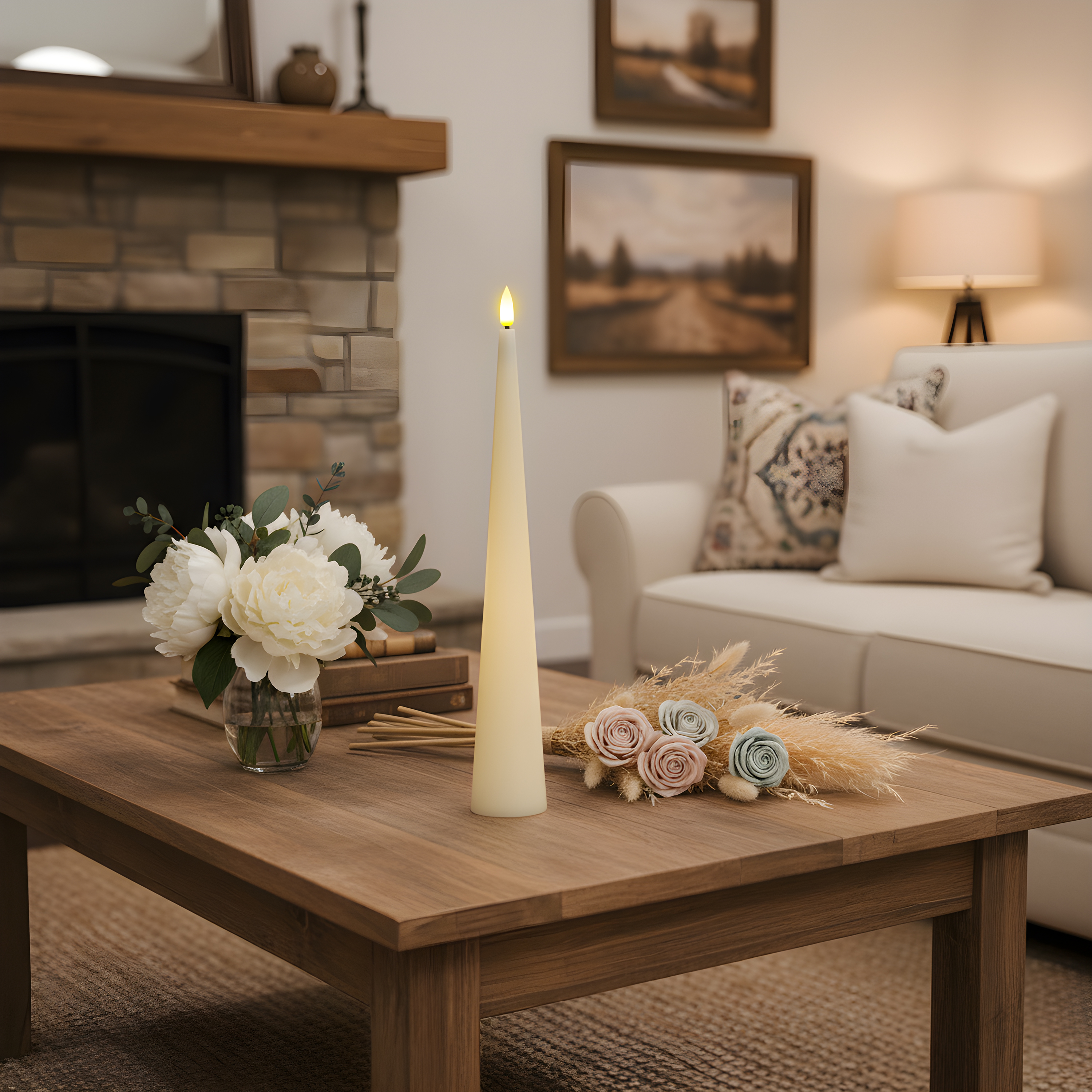 A wooden coffee table with a white candle, flowers in a vase, and dried florals in a cozy living room setting.