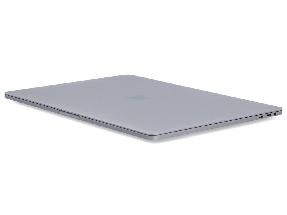 Zamkniety szary laptop lezy na bialej powierzchni z widocznymi portami.