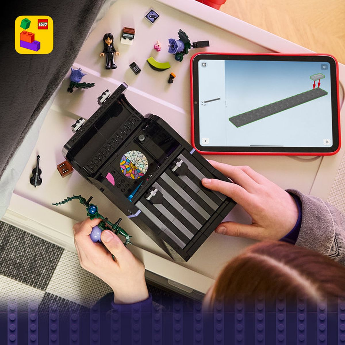 Bir çocuk, talimatları gösteren bir tabletle siyah bir LEGO seti kuruyor.
