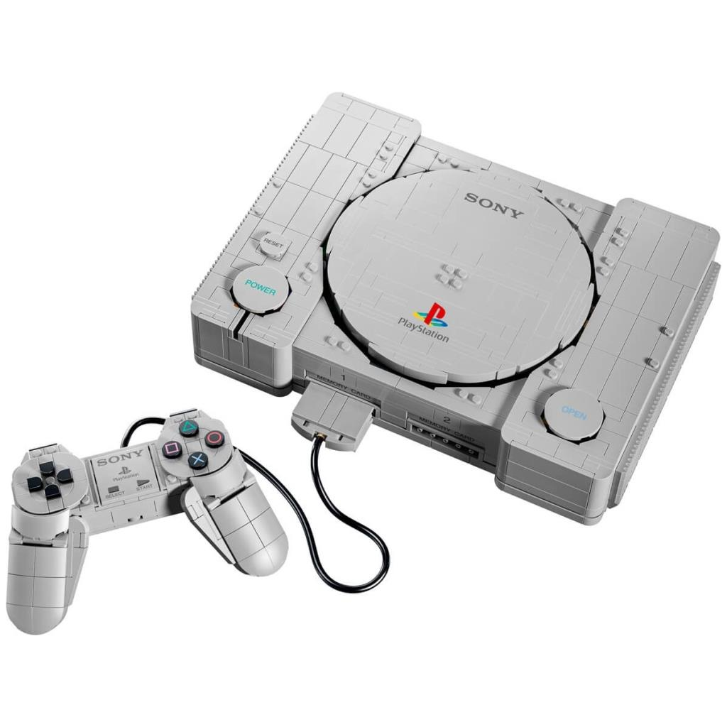 Beyaz arka planda Lego tuğlalarından yapılmış gri bir PlayStation konsolu ve kontrolcüsü.