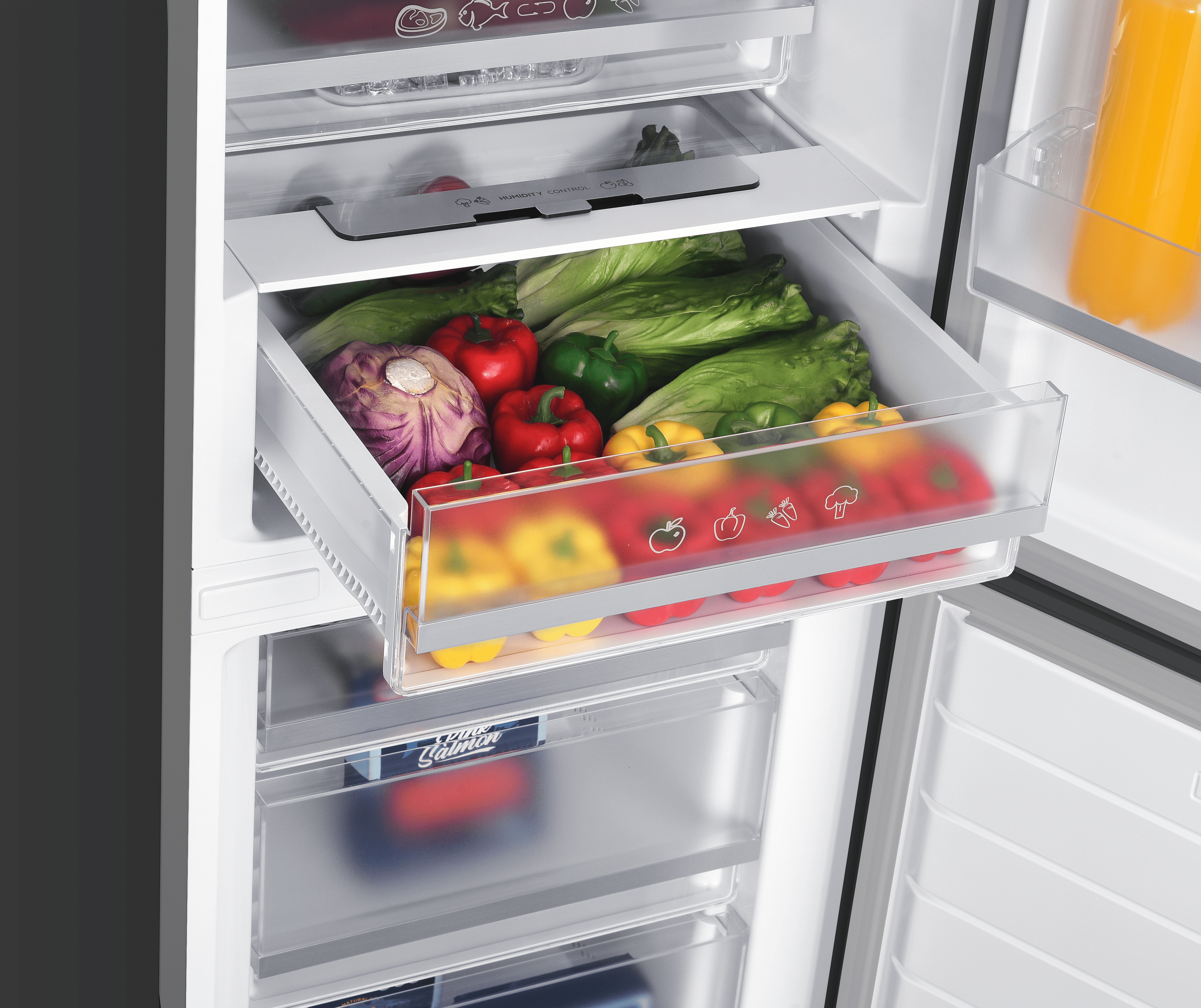 An open refrigerator crisper drawer filled with fresh lettuce, red and yellow bell peppers, and red cabbage.