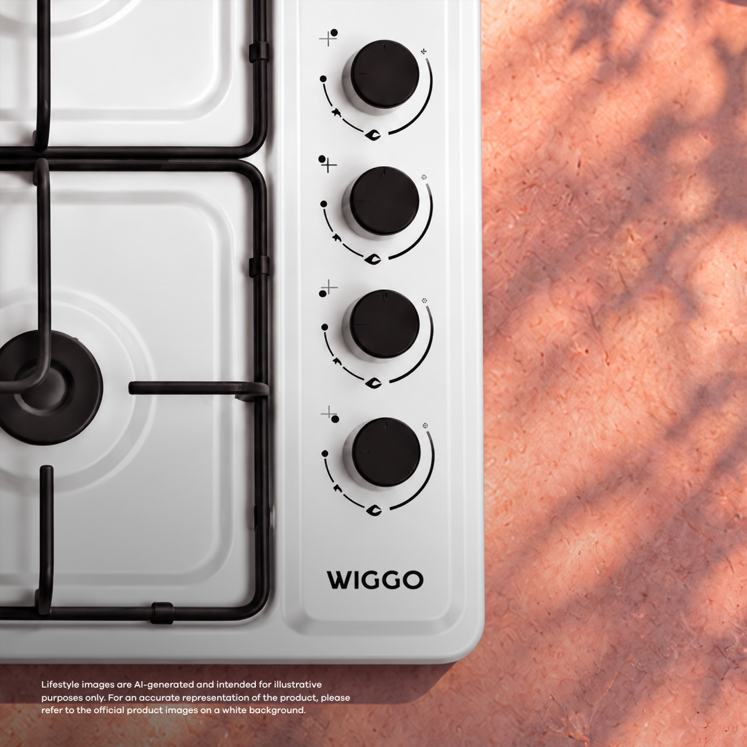 Close-up of a white Wiggo gas hob with black control knobs and cast iron grates against a pink background.