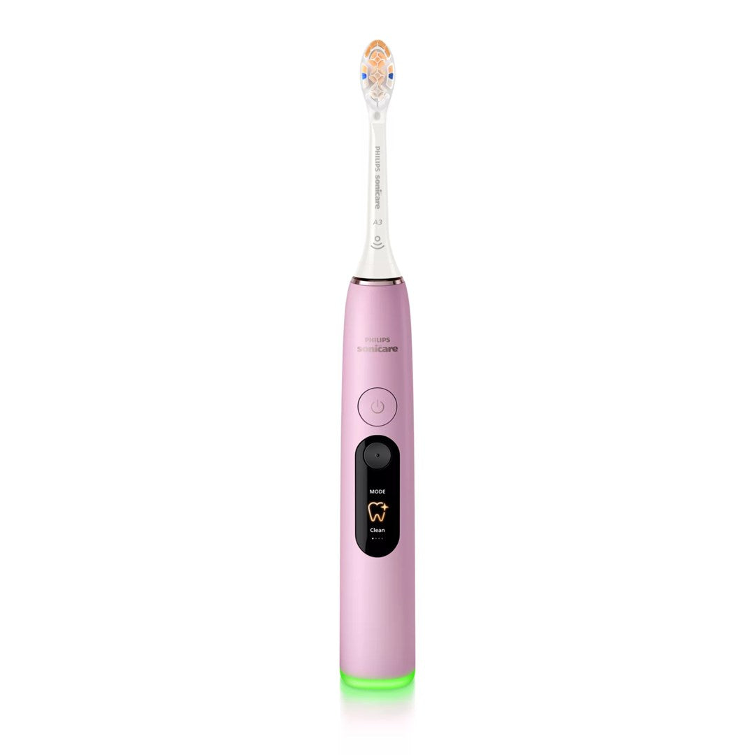 Uno spazzolino elettrico Philips Sonicare rosa con display e luce verde alla base su sfondo bianco.