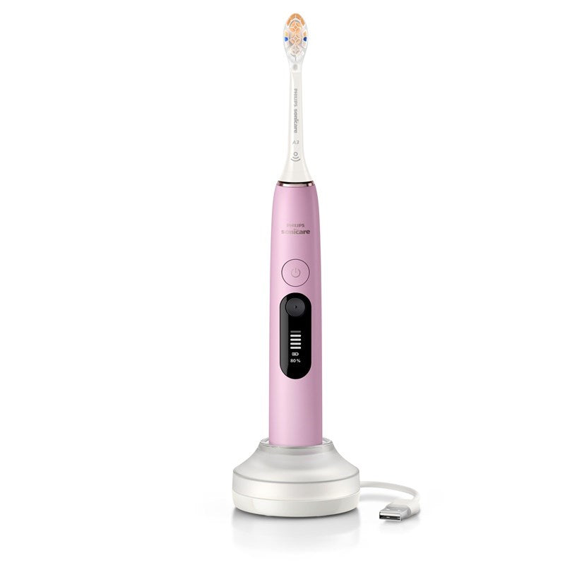 Uno spazzolino elettrico Philips Sonicare rosa su una base di ricarica bianca con cavo USB.
