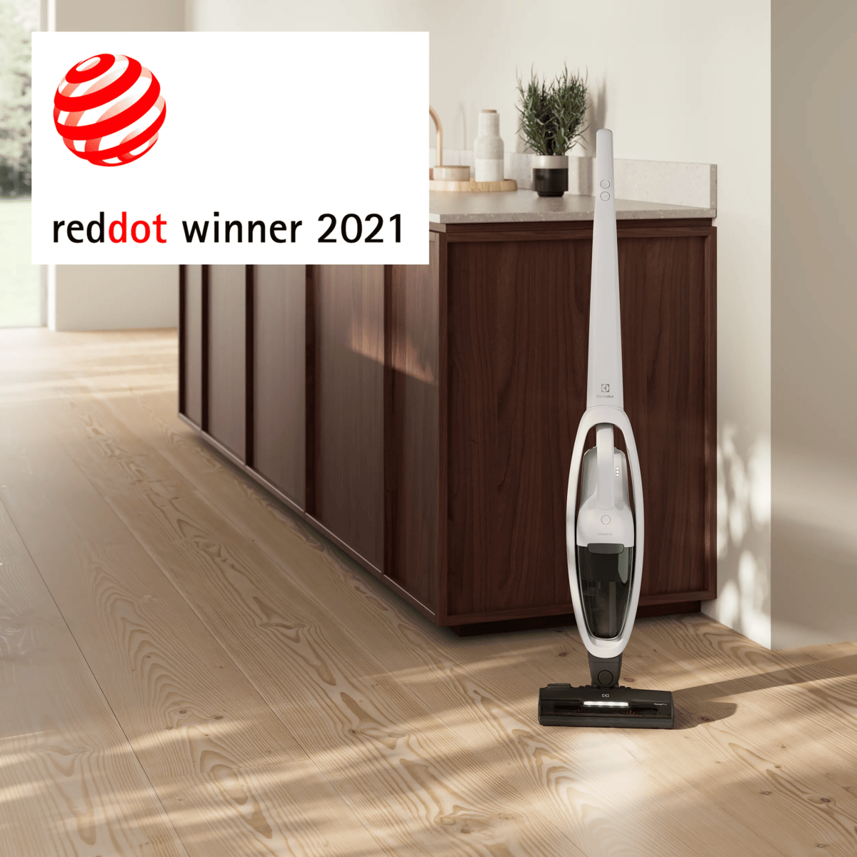 Un aspirapolvere senza fili bianco su pavimento in legno in cucina, con l'etichetta Red Dot Winner 2021 a sinistra.