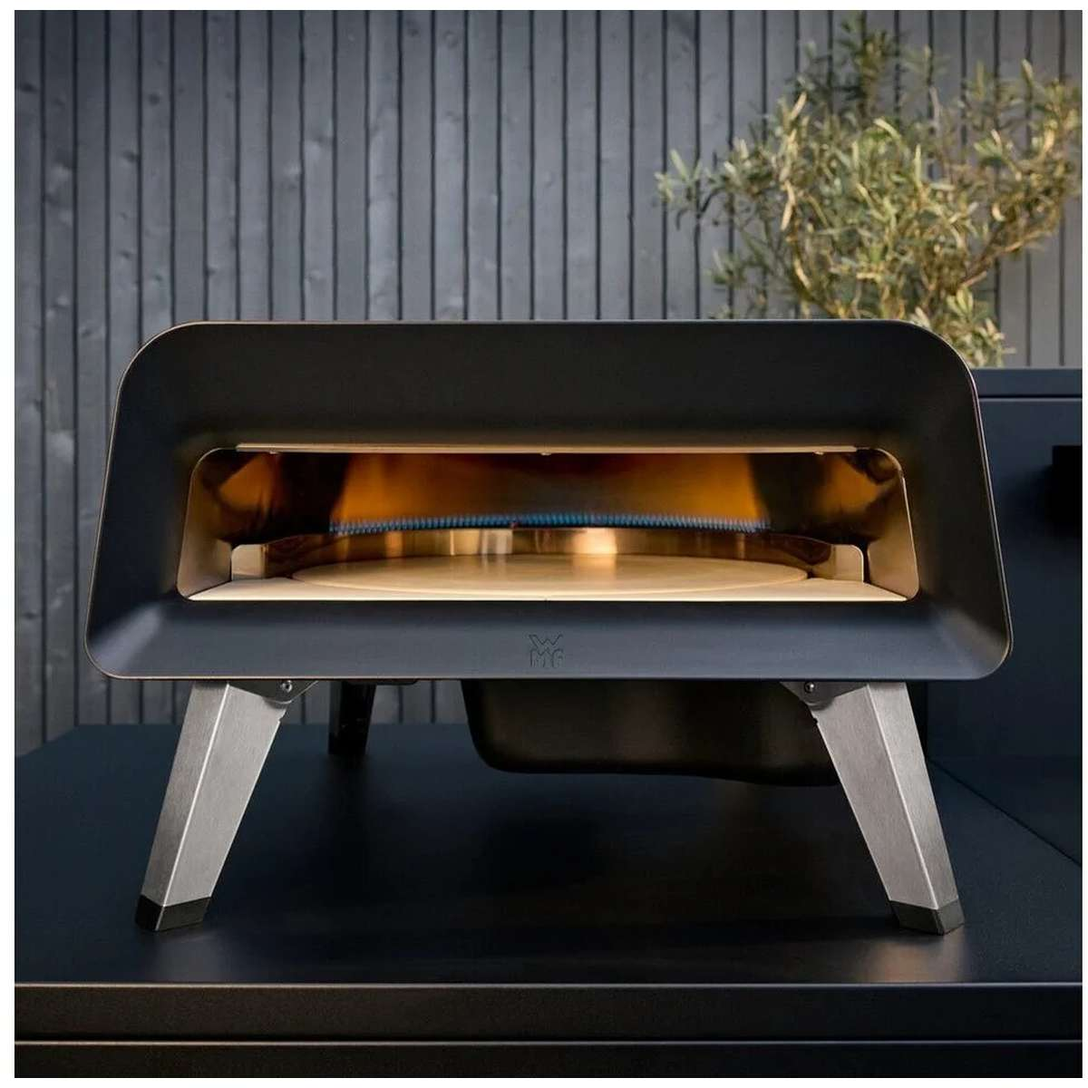 Un forno per pizza portatile nero su superficie scura con fiamme visibili all'interno.