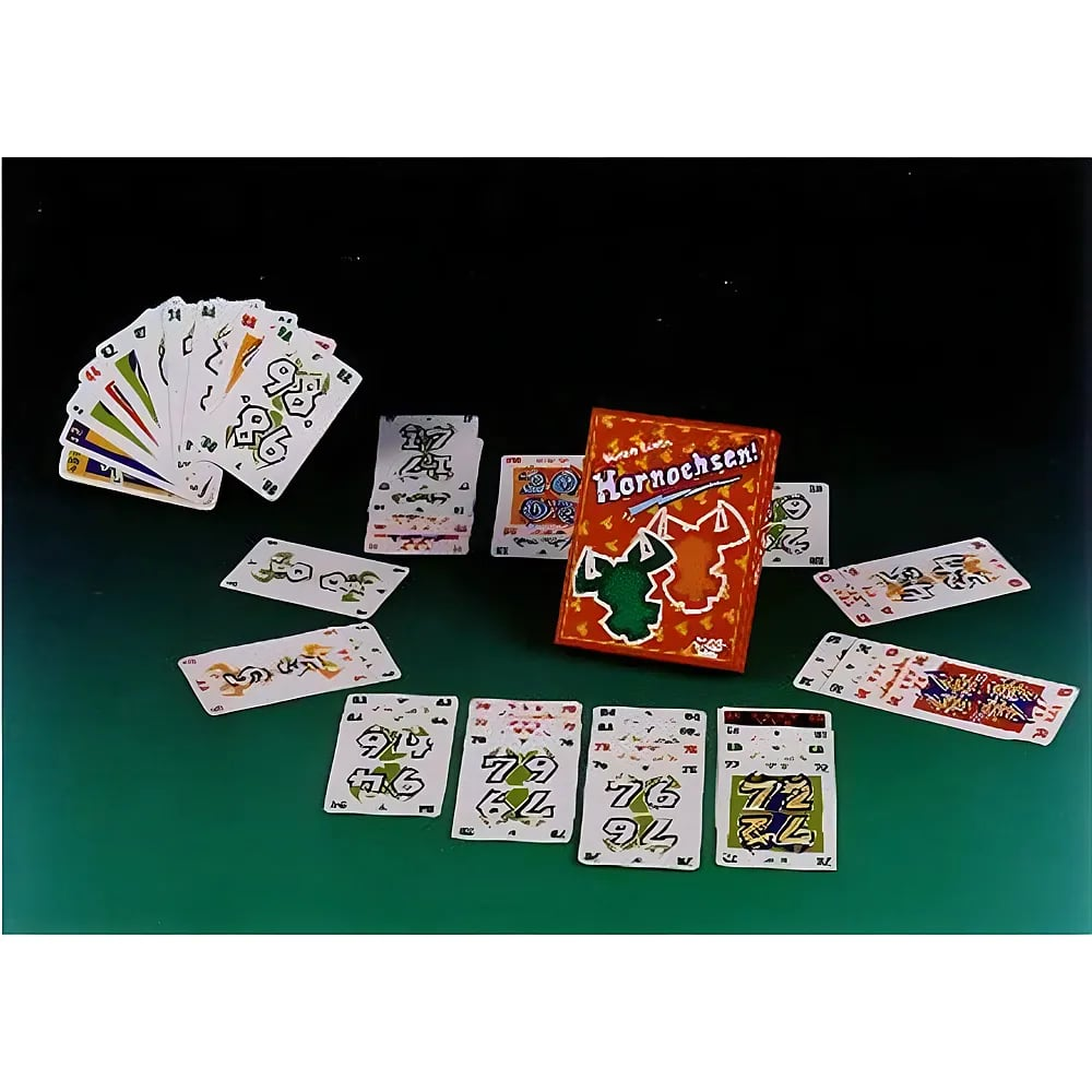 Ein Hornochsen Kartenspiel liegt ausgebreitet auf einem Tisch mit roten und grünen Zahlenkarten und der roten Verpackung.