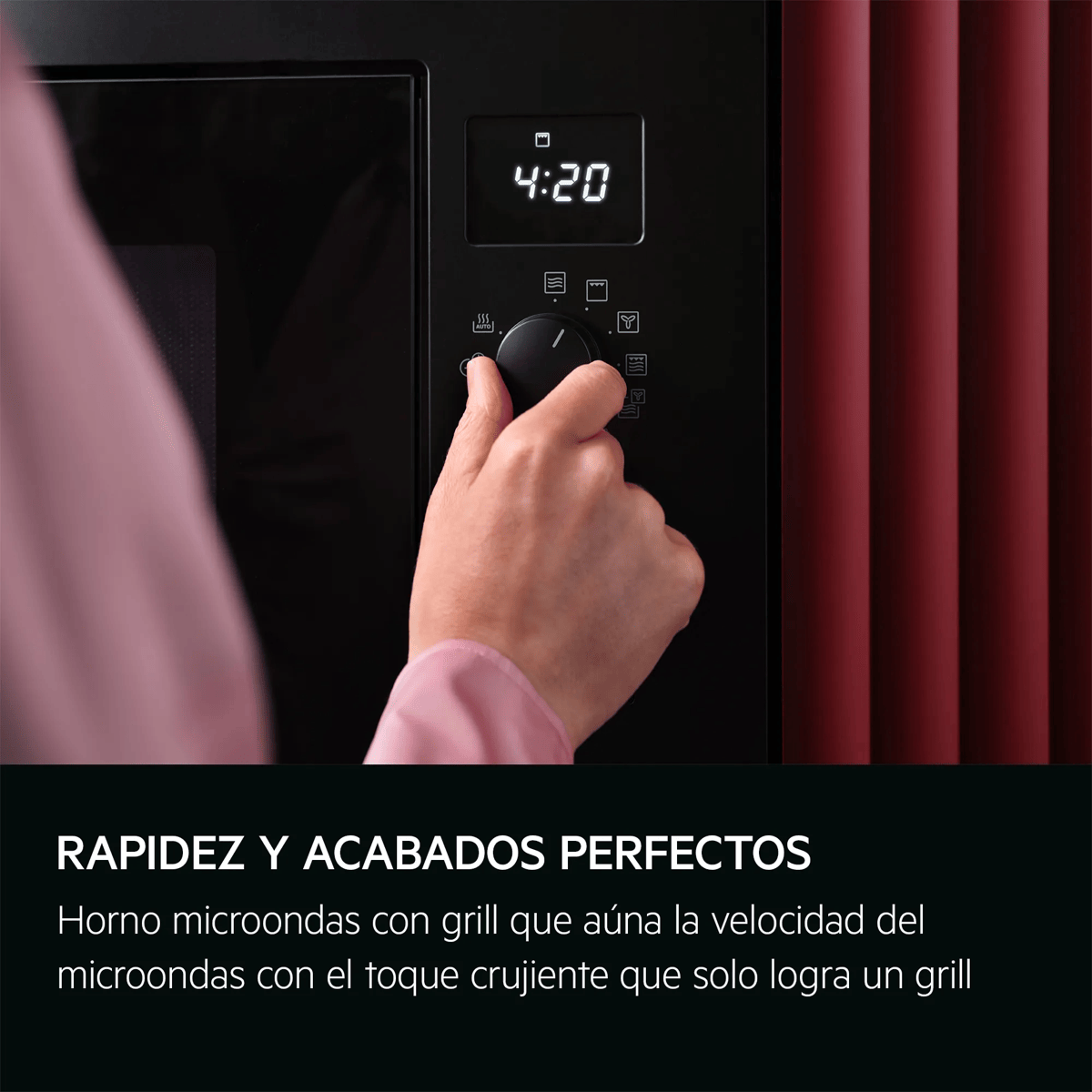 Una mano regola un microonde nero con display digitale ed elementi murali rossi sullo sfondo.