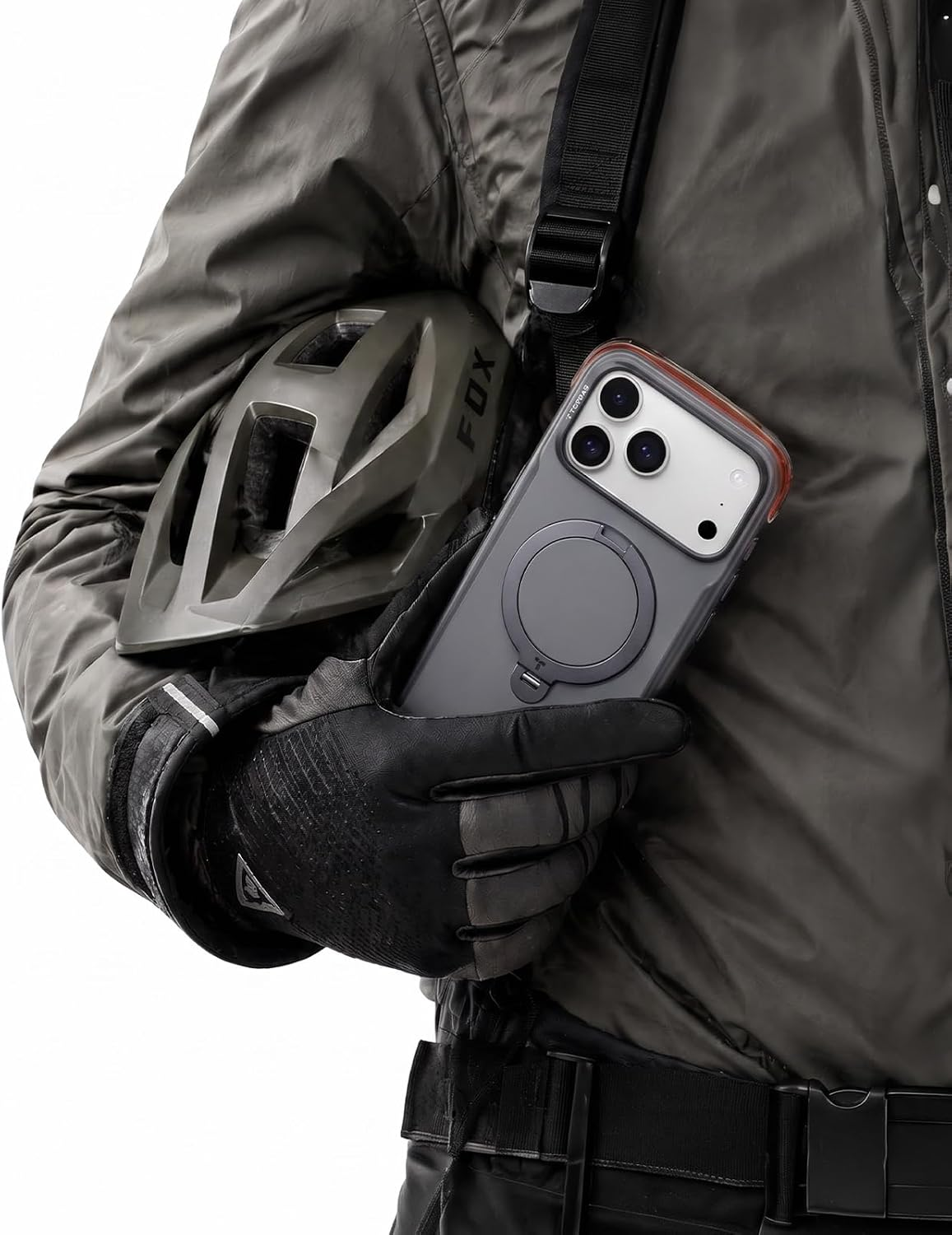 Eine Person im grauen Mantel hält ein Smartphone und einen Helm, trägt schwarze Handschuhe.