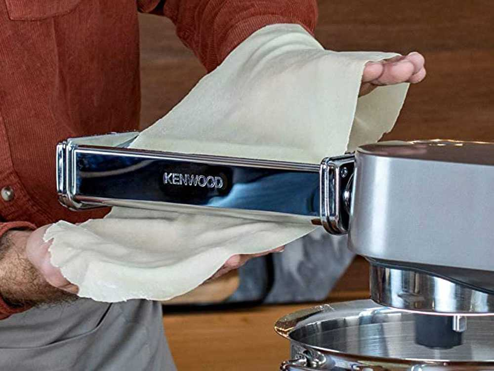 Eine Person nutzt einen Kenwood-Nudelvorsatz, um Teig zu rollen.