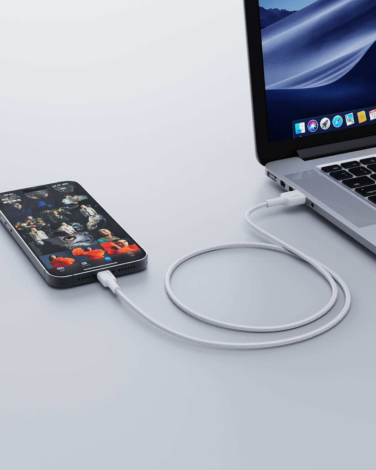 Bir akıllı telefon beyaz bir kabloyla dizüstü bilgisayara bağlı.