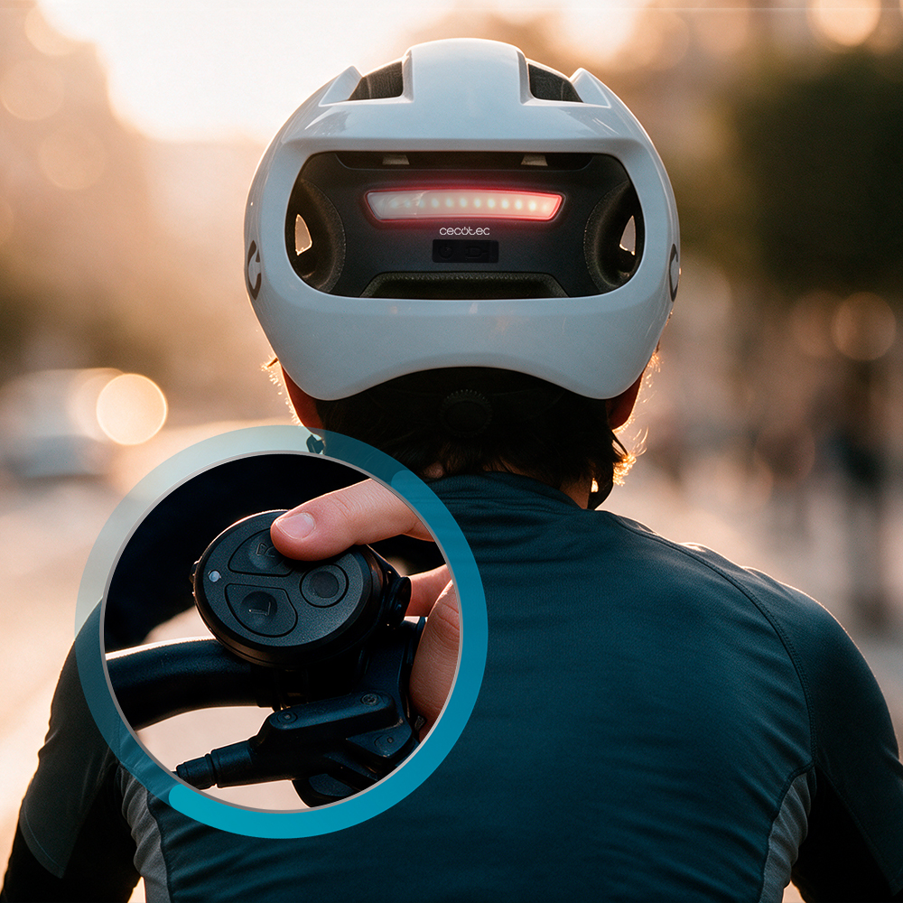 Un ciclista con casco blanco y luz trasera roja, con un detalle que muestra el control del manillar.