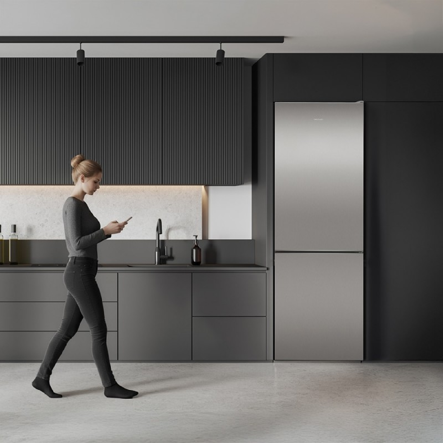 Una mujer en una cocina oscura moderna camina mientras mira su teléfono inteligente.