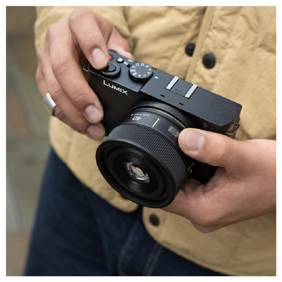 Osoba trzymająca czarny aparat Lumix z obiektywem.